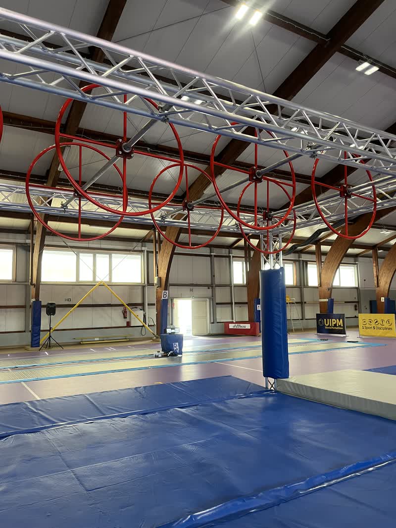 Czerwone koła pod kratownicą w hali zawodów pięcioboju